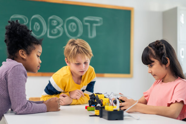 一群小学生在教室里一起学习。在幼儿园的教室里，可爱的孩子们坐在桌子上，快乐地和老师一起学习。图片下载