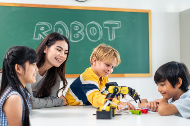 一群小学生在教室里跟着老师学习。迷人美丽的女指导老师在幼儿园用快乐有趣的活动为幼儿讲解和教育。图片下载