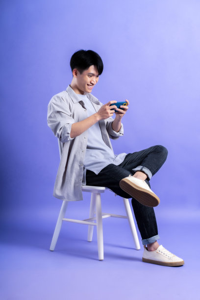 年轻的亚洲男子在紫色背景下使用手机的全身图像图片下载