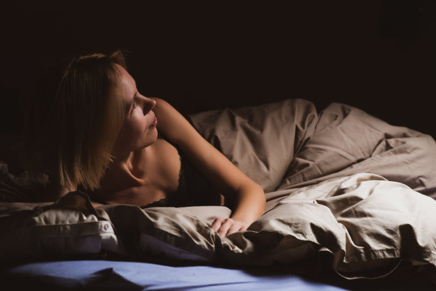 黑暗中躺在床上的女人是睡不着的。失眠，睡眠障碍，昼夜节律的概念。图片下载