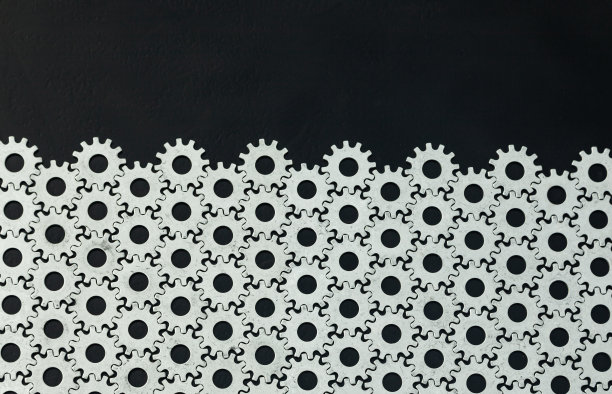 齿轮的背景。大量的钢齿轮相互连接在一个黑色的背景。图片下载