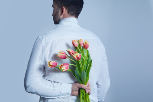 一个男人背着一束红色的郁金香。庆祝妇女节，母亲节。情人节。图片下载