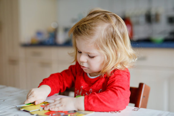 可爱的小蹒跚学步的女孩金发的孩子，玩拼图在家里或幼儿园。可爱快乐健康的孩子困惑和制作图片。宝宝的发展和教育步骤图片下载