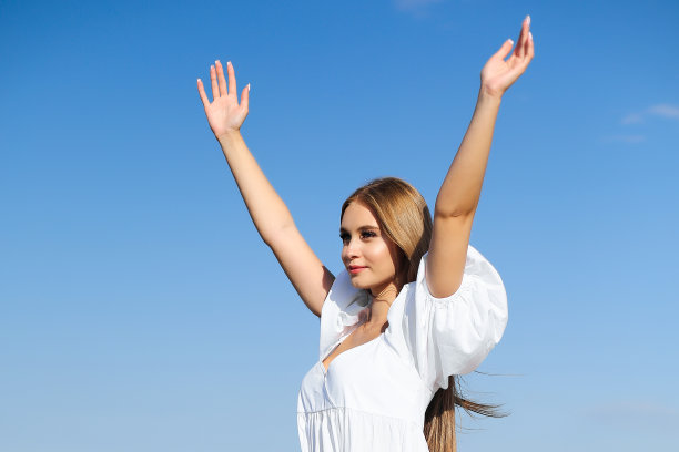 幸福，美丽的女人站在海滩上，穿着白色的夏装，举起双手图片下载