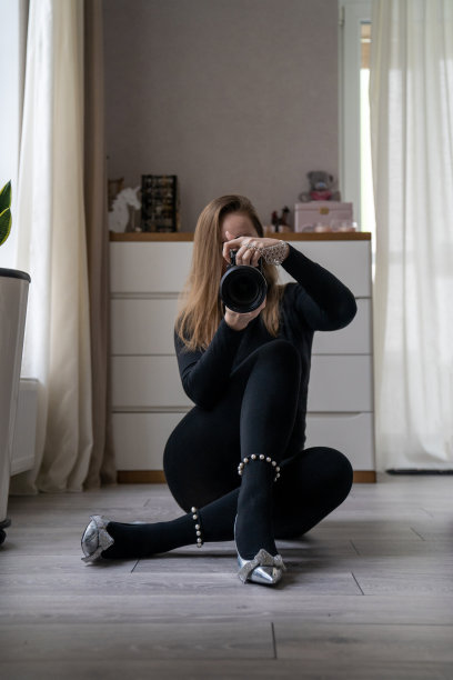 穿着黑色外套和银色鞋子的时尚女子坐在地板上，摄影师在镜子里看着自己，镜子自拍，女士在家里拍摄自己图片下载