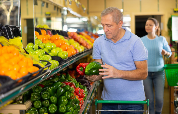 忙碌的老男人推着购物车，在杂货店买当地的灯笼椒图片下载