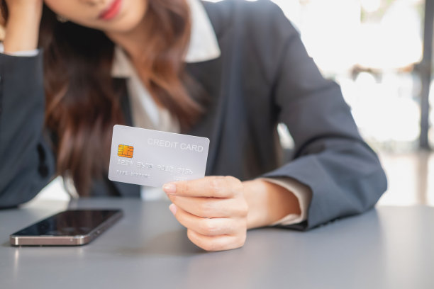 年轻的亚洲女子用信用卡在网上购物。为在线支付的房子内信用卡支付概念图片下载