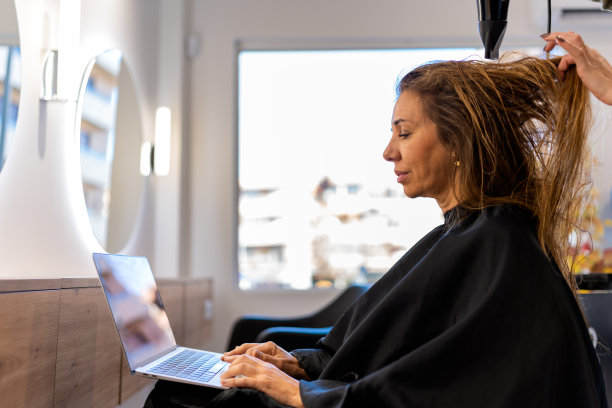 女人坐在理发店里用笔记本电脑工作图片下载