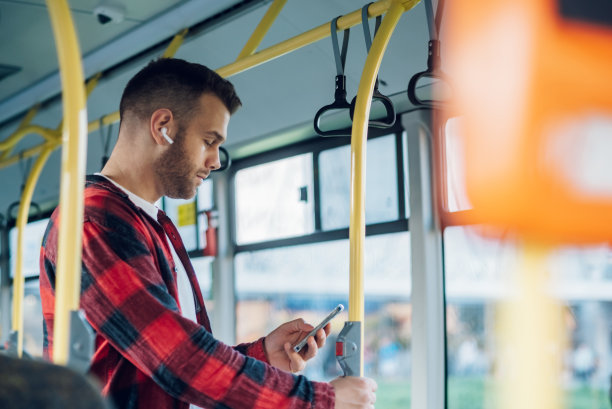 一名男子在乘坐公交车时使用智能手机图片下载