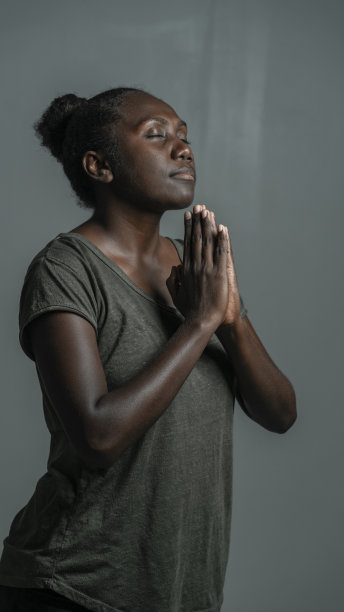 黑皮肤女模特站着闭着眼睛祈祷的姿势。图片下载