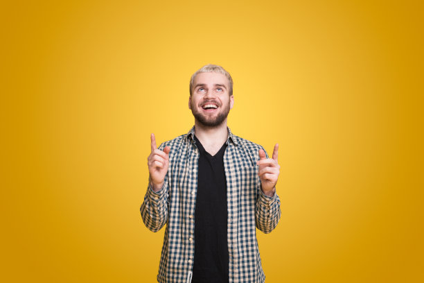 一个快乐的白人男子指着黄色背景上孤立的复制空间的肖像。指向上。孤立的肖像。副本的空间。图片下载