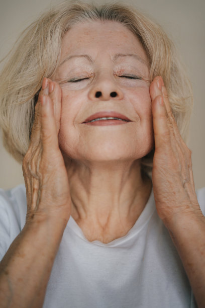 美丽的老年妇女的肖像轻轻适用下眼睛面霜。老年妇女使她的皮肤柔软。天然抗衰老化妆品，无皱纹图片下载