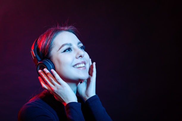 一个快乐的年轻白人妇女的工作室肖像听音乐与无线耳机图片下载