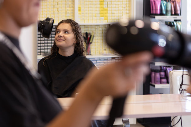 理发师在发廊为青少年吹干头发图片下载