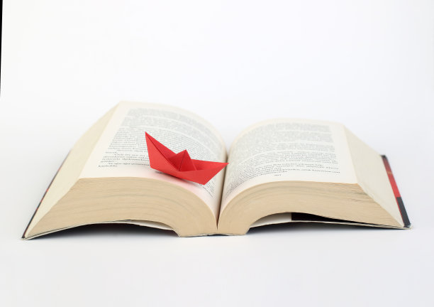 红色的折纸船漂浮在书页上。学习，教育，读书，知识观念图片下载