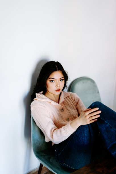 年轻的亚洲女性戴着耳机听音乐，在沙发上跳着充满活力和节奏的舞蹈。迷人的亚洲女孩看着智能手机坐在客厅里度过闲暇时间在家里图片下载