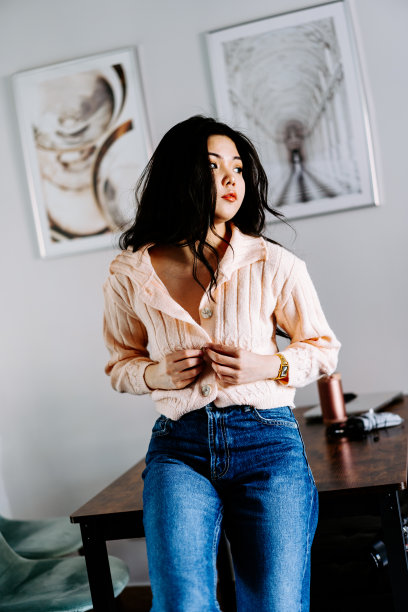 年轻的亚洲女性戴着耳机听音乐，在沙发上跳着充满活力和节奏的舞蹈。迷人的亚洲女孩看着智能手机坐在客厅里度过闲暇时间在家里图片下载