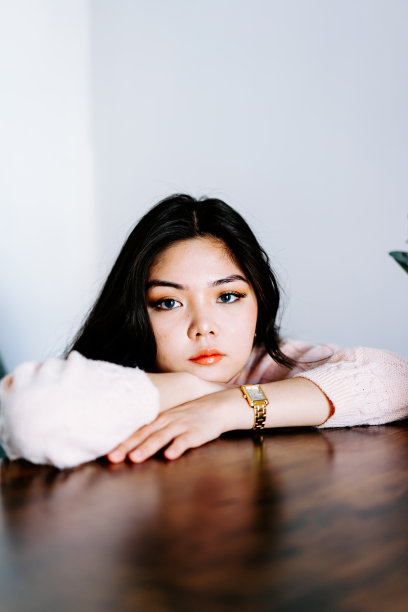 年轻的亚洲女性戴着耳机听音乐，在沙发上跳着充满活力和节奏的舞蹈。迷人的亚洲女孩看着智能手机坐在客厅里度过闲暇时间在家里图片下载