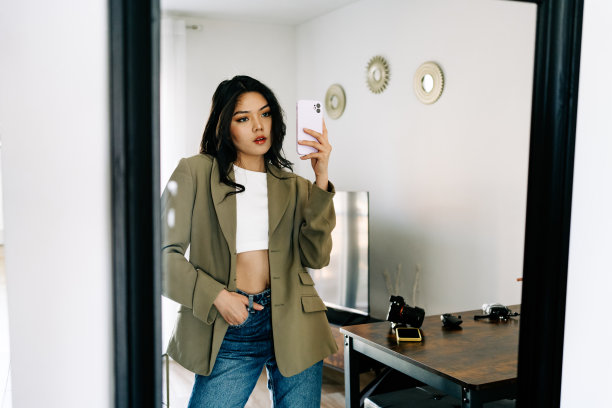 年轻的亚洲女性戴着耳机听音乐，在沙发上跳着充满活力和节奏的舞蹈。迷人的亚洲女孩看着智能手机坐在客厅里度过闲暇时间在家里图片下载