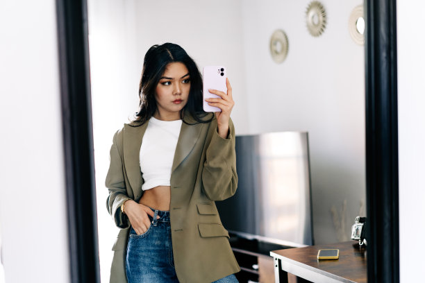 年轻的亚洲女性戴着耳机听音乐，在沙发上跳着充满活力和节奏的舞蹈。迷人的亚洲女孩看着智能手机坐在客厅里度过闲暇时间在家里图片下载