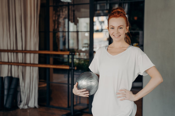 积极的健身教练姜头发摆姿势与小银色健身球在手图片下载