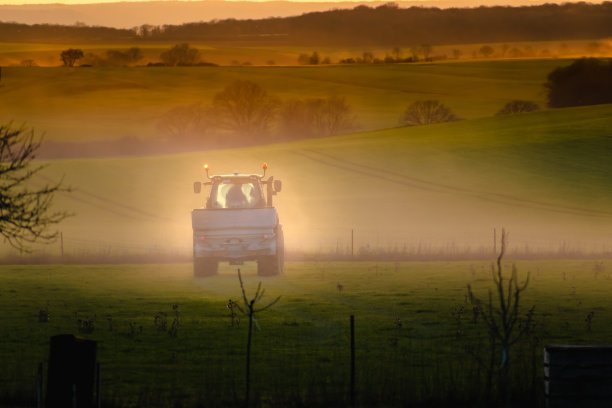 拖拉机在夕阳下的土壤地里工作，大设备，乡村风光图片下载