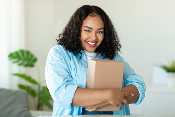 快乐的非裔美国妇女拥抱纸板箱抱包裹室内图片下载