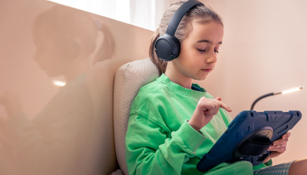 小女孩戴着耳机，房间里放着平板电脑。图片下载