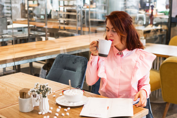 年轻漂亮的女子在咖啡馆喝咖啡吃早餐。图片下载