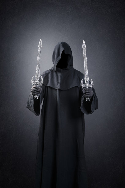 黑暗骑士与兜帽斗篷和两把剑在黑暗朦胧的背景图片下载