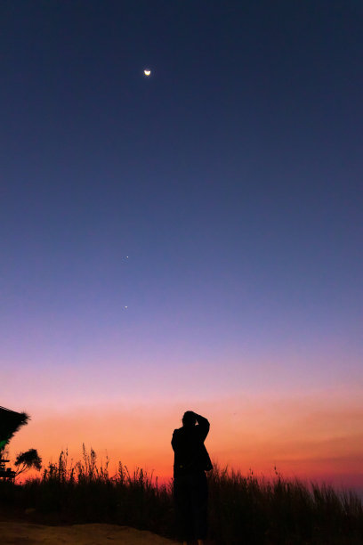 女性用星星、行星和月牙观察夜空，拍摄大自然的照片。月亮在黄昏的天空中与木星和金星相遇。图片下载