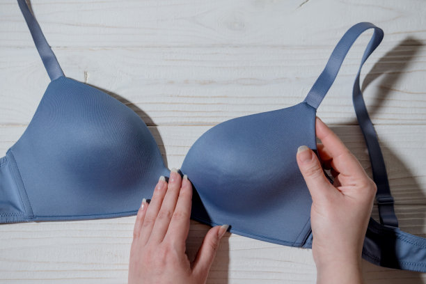 女人拿着蓝色胸罩，木制背景，特写图片下载