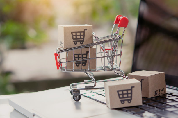 网上购物。在笔记本电脑键盘上的手推车上有购物车标志的纸板箱。网上购物服务。提供送货上门服务图片下载