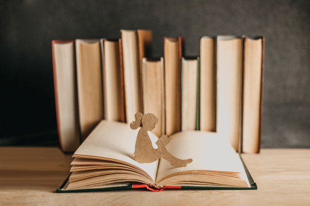 一个女孩坐在打开的书上读书的纸雕像图片下载