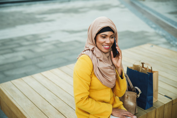 戴头巾的黑人穆斯林妇女在街上使用智能手机图片下载