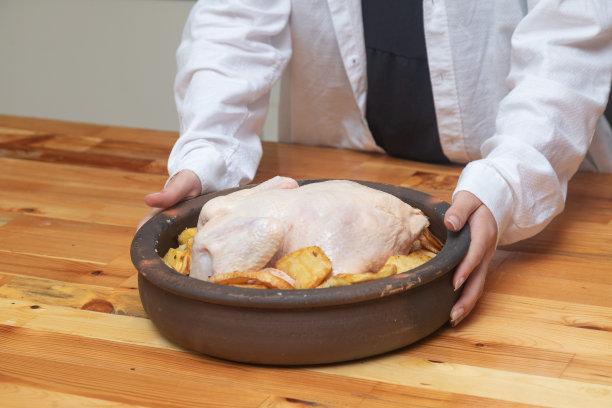 女人拿着锅在厨房柜台鸡肉菜生土豆高分辨率图片下载