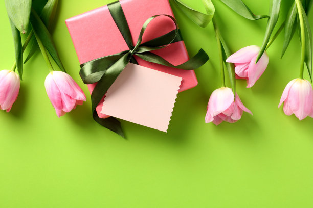 礼盒与贺卡模型和春天的花朵在绿色的桌子上。图片下载