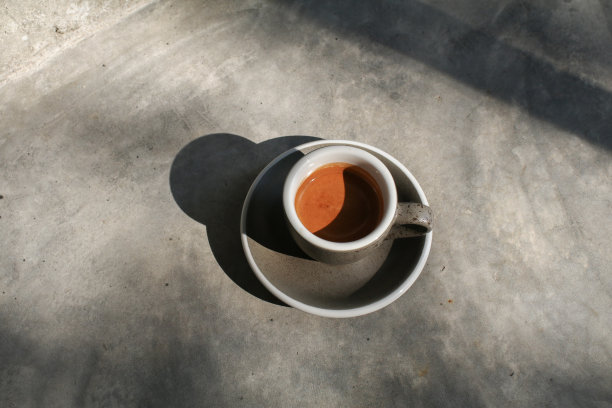 咖啡杯放在桌子上，阳光下有阴影。极简的一杯拿铁与长阴影。晨间咖啡，用白色杯子装蒸汽。图片下载