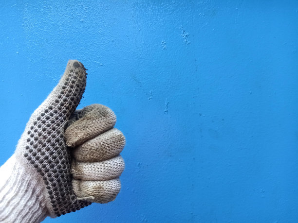 男子戴着工作手套，大拇指在蓝色背景上孤立地向上。完成工作后表现出积极的态度。工作好，心情愉快，有认可的观念。本空间图片下载