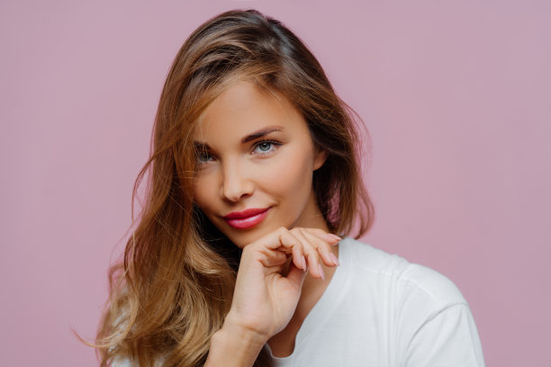 横向视图，迷人的年轻女子长发，美甲和化妆，自信地看着相机，穿着白色毛衣，在紫色背景下摆姿势，享受业余时间。美丽的概念图片下载