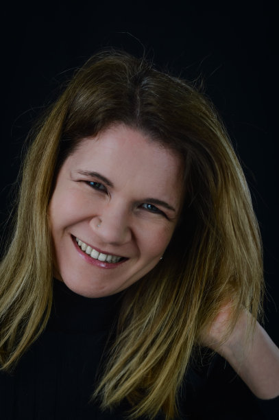 一个美丽的微笑金发女人的肖像安排她的头发在运动与她的手图片下载