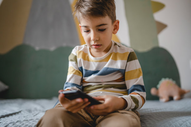 一个白人男孩在家里用智能手机玩游戏图片下载