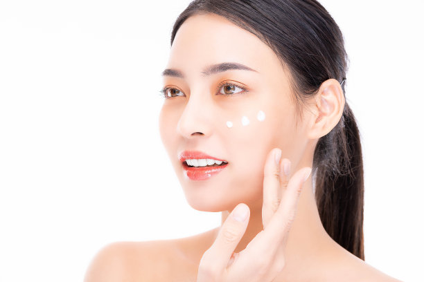 美丽的年轻亚洲女子应用美容治疗霜在美丽的脸隔离在白色背景美丽的微笑亚洲模特肖像与自然妆容她触摸发光湿润的皮肤图片下载