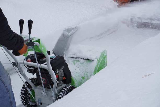 冬天，一名男子在房子的院子里清理积雪，他用吹雪机清理积雪图片下载