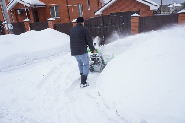 冬天，一名男子在房子的院子里清理积雪，他用吹雪机清理积雪图片下载