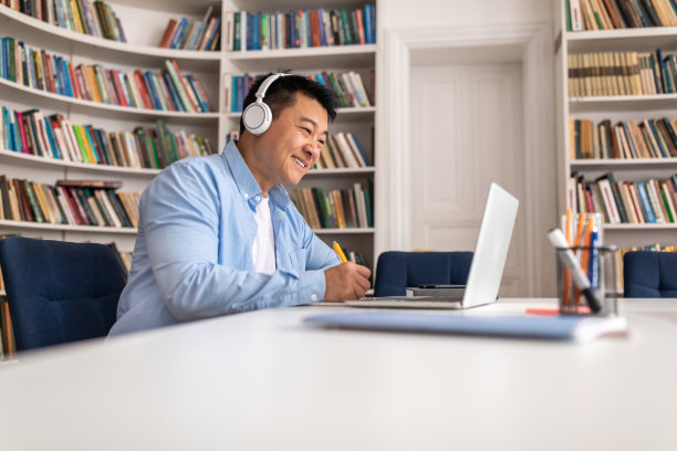 快乐的亚洲人在图书馆用笔记本电脑做笔记图片下载