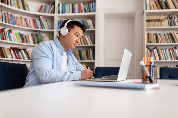 亚洲商人在办公室里用笔记本电脑做笔记图片下载