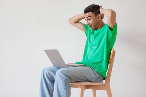 震惊的内容：阿拉伯男子看着笔记本电脑屏幕，摸着头，对新闻做出情绪化的反应图片下载