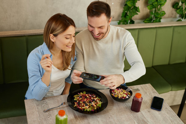 中年成年夫妇在沙拉吧用智能手机拍摄沙拉图片下载
