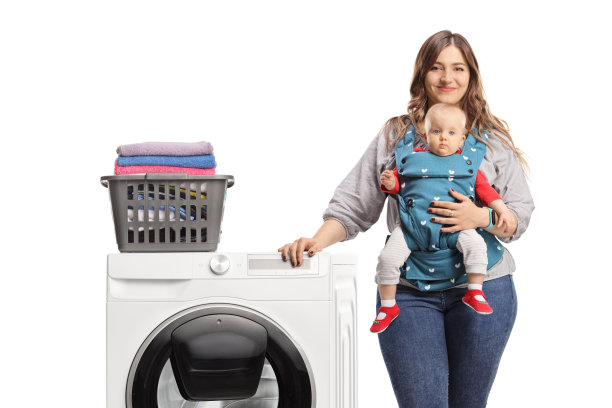 母亲带着一个婴儿靠在洗衣机和洗衣篮上图片下载